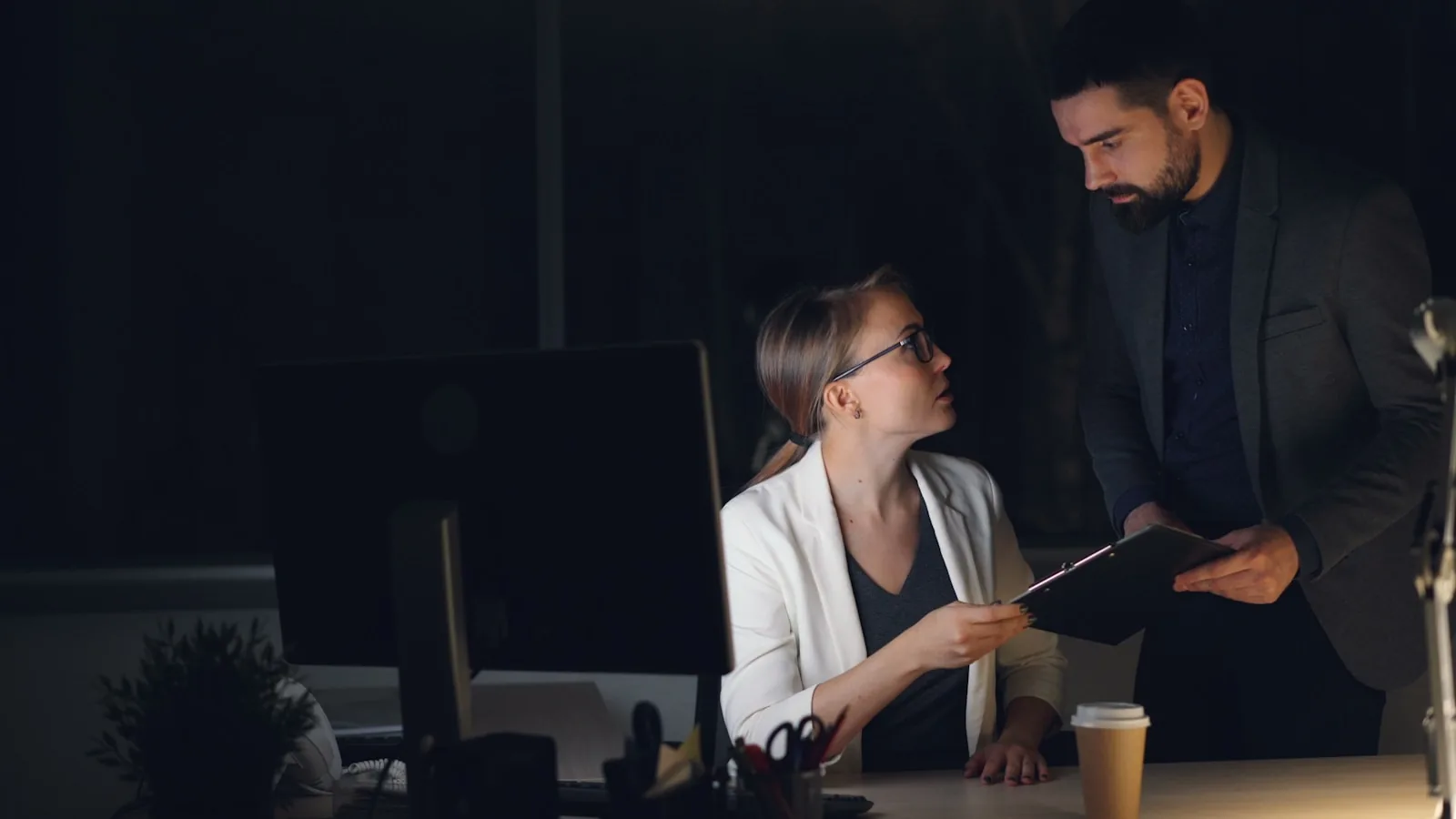 Two colleagues working late in a dimly lit office.