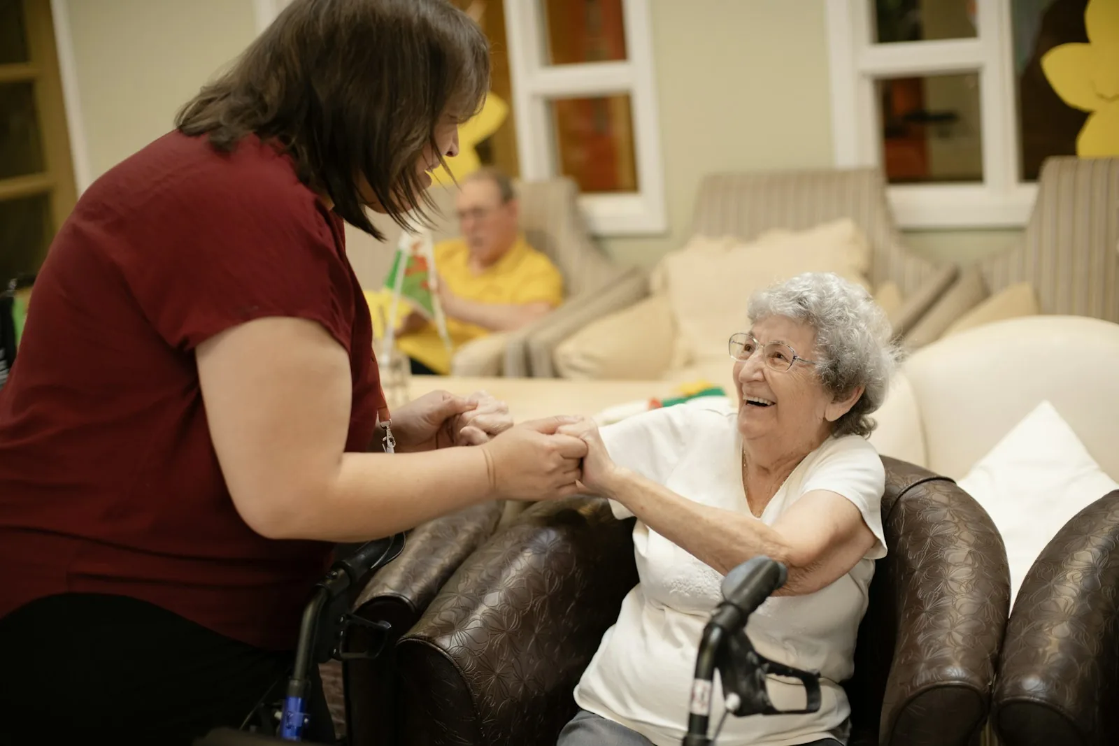 Caregiver assists elderly woman with walker.
