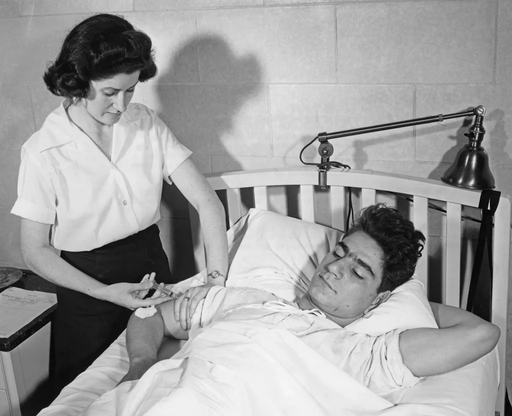 Nurse gives injection to patient in bed
