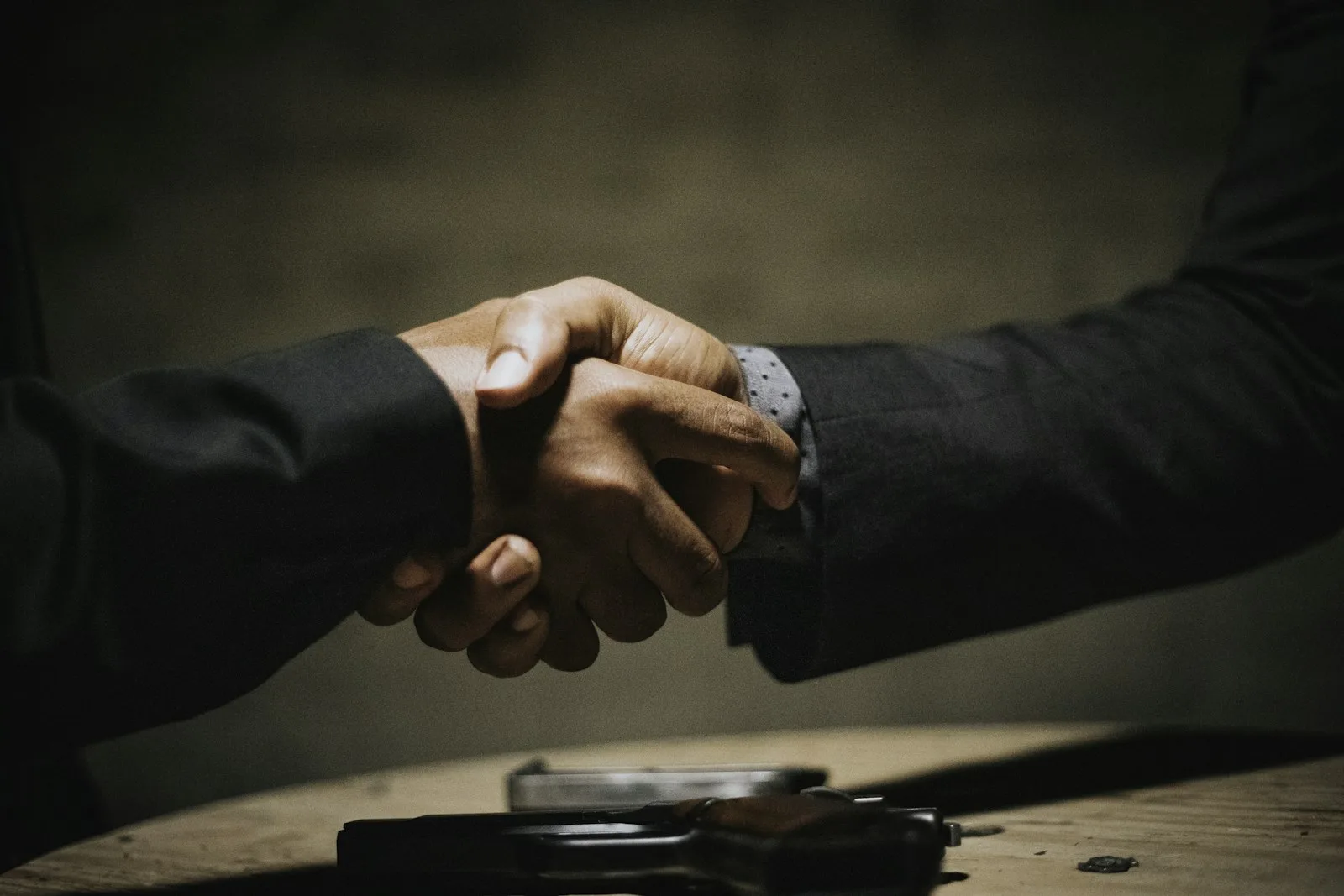 two people shaking hands over a wooden table