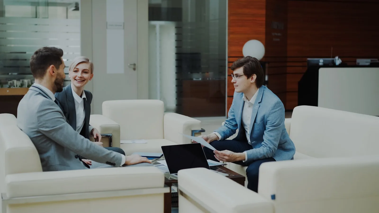 Three professionals in a modern office lounge.
