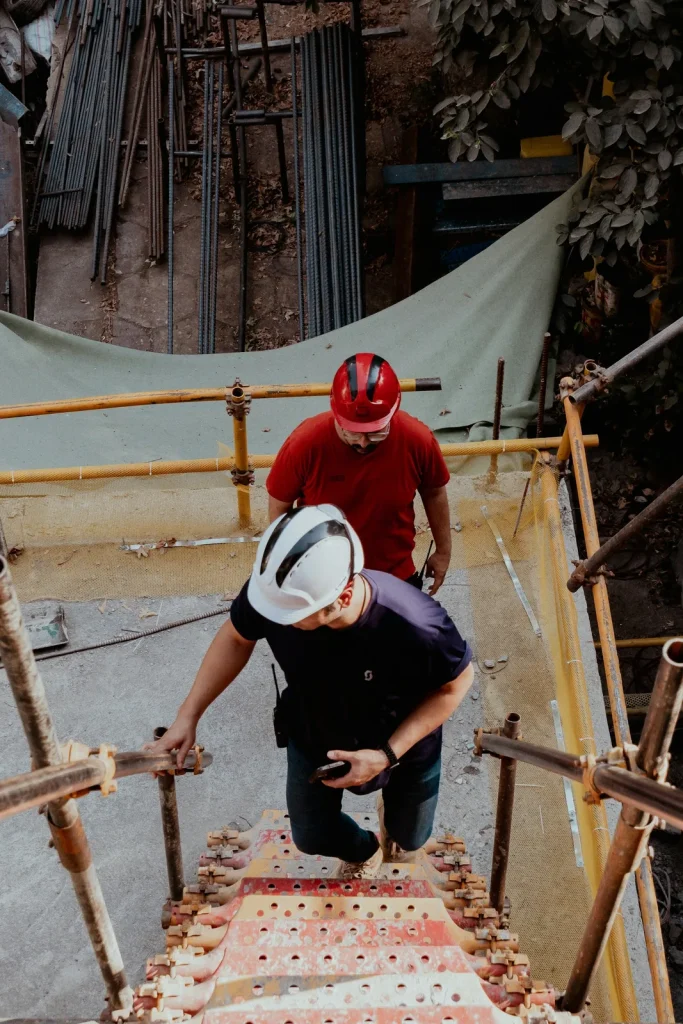 Men in hard hats ascend construction site stairs.
