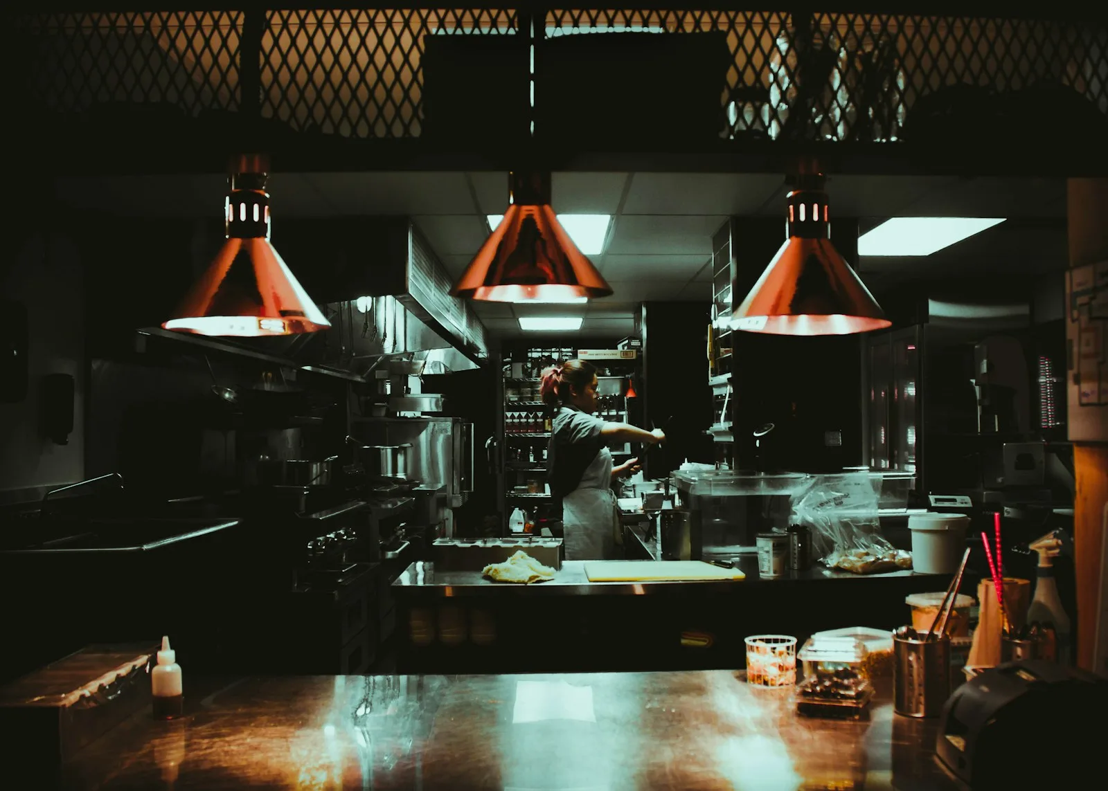 woman standing near three red pendant lamps