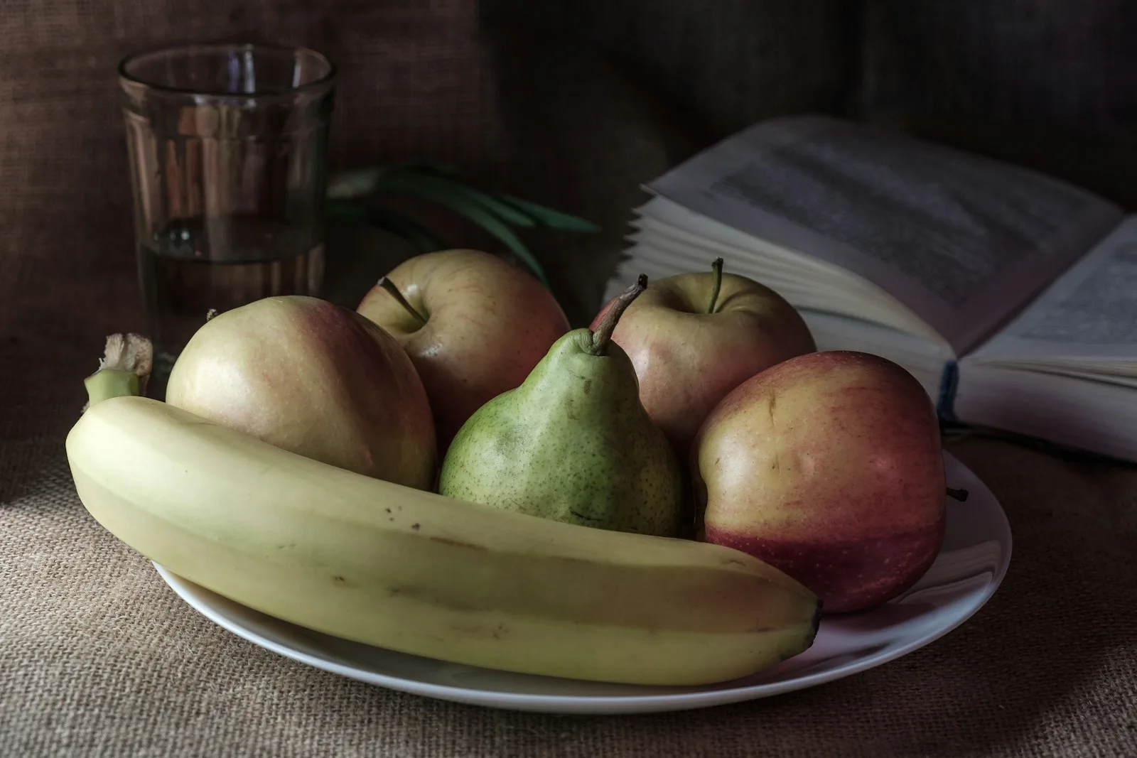 Still life of fruit with a glass and book.