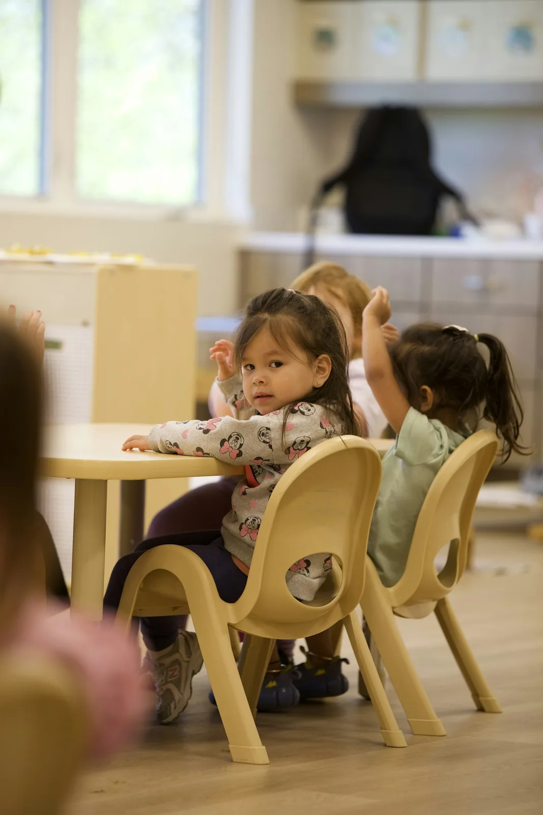 Young children sitting at a table in a classroom.
