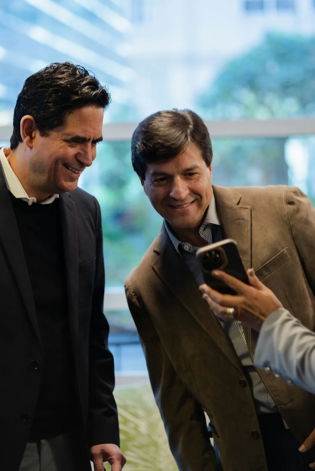 Two smiling men look at a smartphone screen.